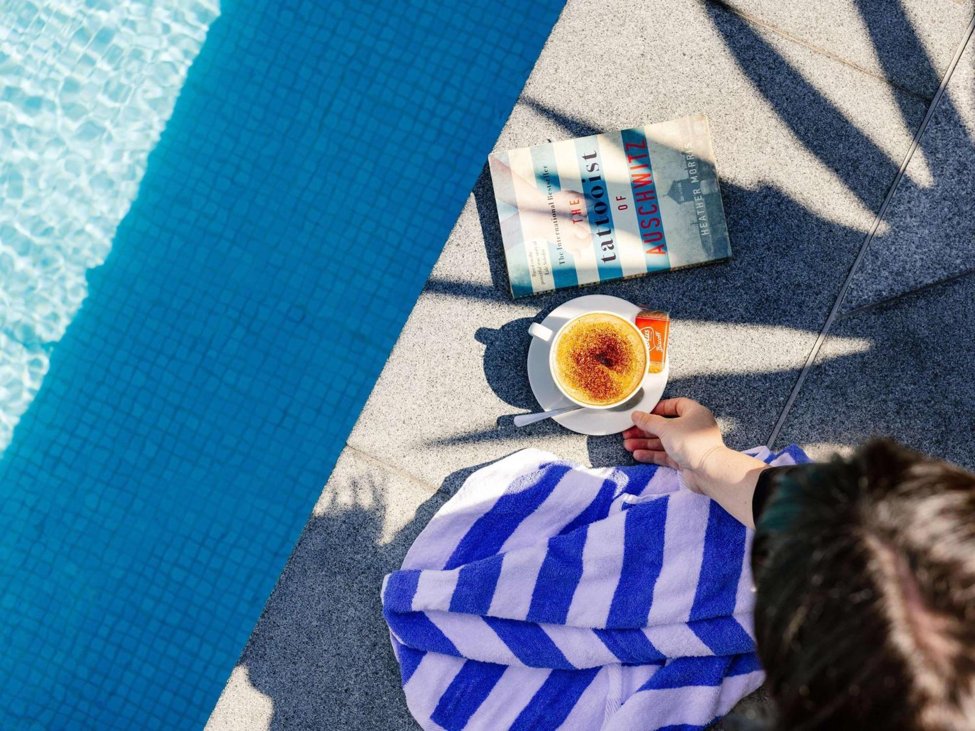 Pullman Brisbane Airport Hotel Exterior photo A woman reading a book by the pool